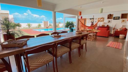 a dining room with a table and chairs and a pool at Villa Paririö in Canoa Quebrada