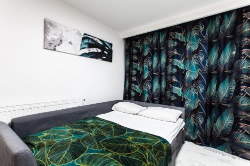1 dormitorio con 1 cama con papel pintado tropical en Zielony Apartament Gliwice en Gliwice