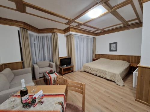 a bedroom with a bed and a couch and a table at Pirin Golf Private Apartments & Studios in Razlog