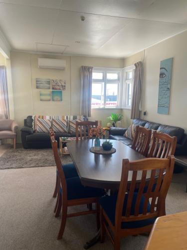 sala de estar con mesa, sillas y sofá en Coastal Accommodation en Oamaru