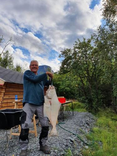 Een man houdt een grote vis vast met een speer. bij Strandbu Camping in Skibotn