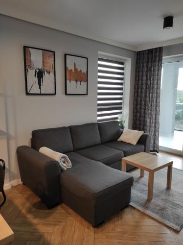 a living room with a couch and a table at Apartament J Towers z widokiem na jezioro in Ełk
