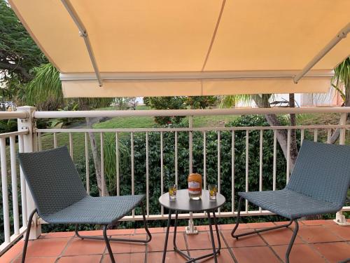 two chairs and a table on a porch with an umbrella at Le Titouloulou 1023 Anse des Rochers in Saint-François