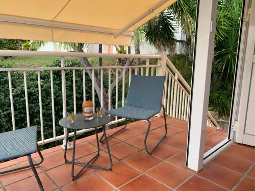 a patio with two chairs and a table on a porch at Le Titouloulou 1023 Anse des Rochers in Saint-François