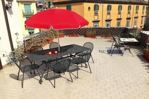 ナポリにあるPanoramico con terrazzoのパティオ(赤い傘付きのテーブルと椅子付)