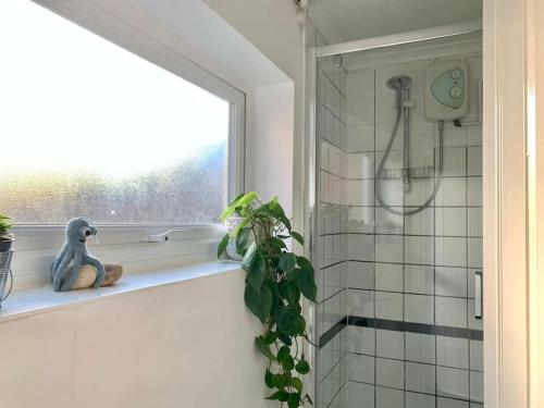a bathroom with a window and a plant on a shelf at Cute Cottage 4 mins from Cafés Station and Sea in St. Leonards