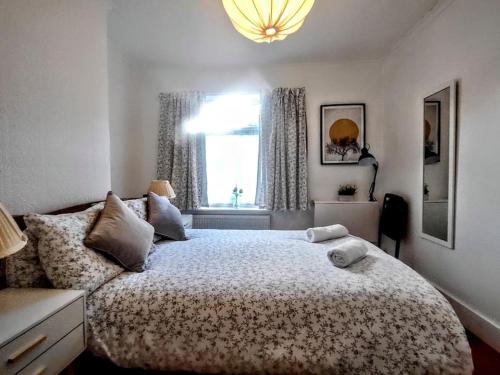 Un dormitorio con una cama grande y una ventana en Cute Cottage 4 mins from Cafés Station and Sea en St. Leonards