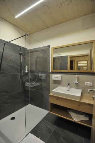 een badkamer met een glazen douche en een wastafel bij Das Dorfhotel Engl-Grafinger in Pinsdorf