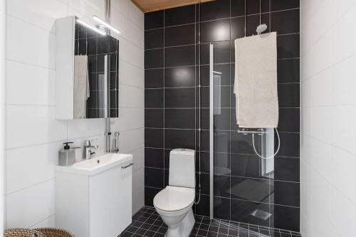 Łazienka wyłożona jest czarnymi kafelkami i dysponuje toaletą oraz prysznicem. w obiekcie New studio Pastel near Helsinki airport in Kivistö w mieście Vantaa