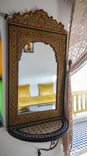 a mirror on a chair with a bed in it at Riad Green House in Fès