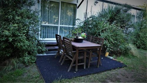 a wooden table with two chairs and a plant on it at Nut Point Cottage in West Melton