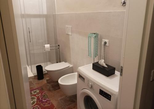 Appartamento in Cascina Cortazza في كريمونا: حمام مع مرحاض وغسالة