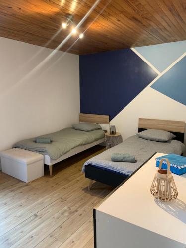 dwa łóżka w pokoju z drewnianym sufitem w obiekcie Le Gîte de Félix - Maison chaleureuse 190m2 - 6 ch - 20pers w mieście Sonnay