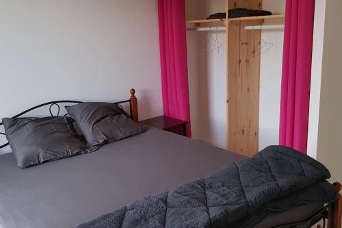 een slaapkamer met een bed met roze en paarse gordijnen bij maison entière 8 couchages in Assieu