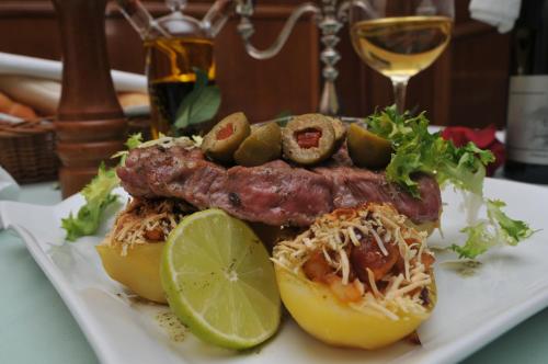 a plate of food with meat and peppers and a glass of wine at Top Penzión Marína in Dolný Kubín