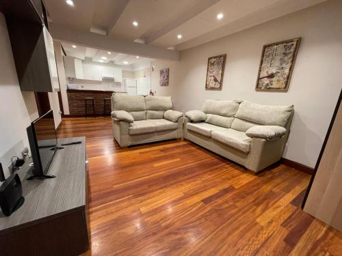 a living room with two couches and a flat screen tv at Compuerta Otañes in Otañes