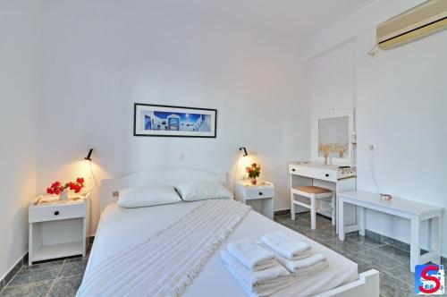 1 dormitorio con 1 cama blanca y 2 mesas blancas en Soultana Rooms & Studios, en Pollonia