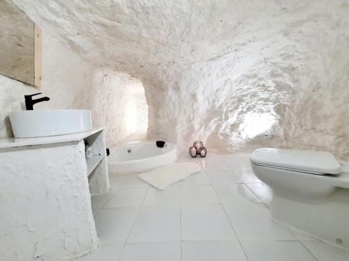a white bathroom with a toilet and a sink at Casa Cueva a 15 minutos del centro de Valencia in Paterna
