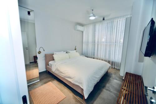 a bedroom with a white bed and a large window at 10 min from Hilton Beach with free parking in Ramat Gan