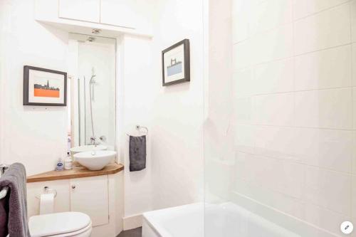 a white bathroom with a toilet and a sink at Central London Warwick Sq, in London