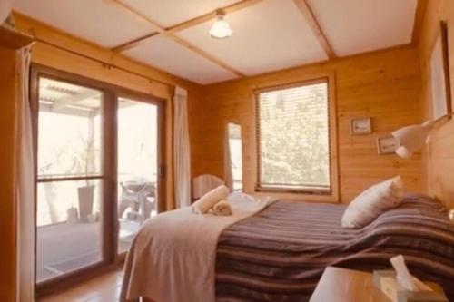 a bedroom with a bed and a large window at Black Wattle Cabin Turon Escape Capertee in Capertee