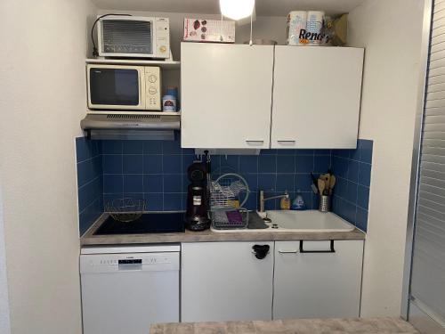 La cuisine est équipée de placards blancs, d'un évier et d'un four micro-ondes. dans l'établissement Appartement port argeles, à Argelès-sur-Mer