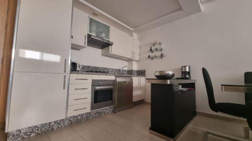 a kitchen with white cabinets and a black refrigerator at Ola Blanca Sidi rahal Apparthotel in Sidi Rahal