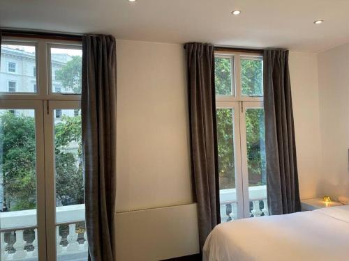 a bedroom with two windows and a bed and a balcony at Designer 2 bedroom Pimlico in London