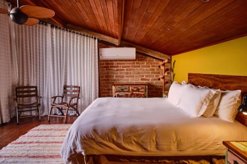- une chambre avec un grand lit et un mur en briques dans l'établissement Pousada Teto do Cafundó, à São Francisco Xavier