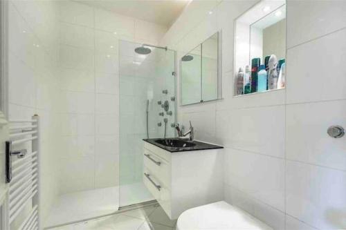 a white bathroom with a sink and a shower at Stunning Grand 2 bed, 2 bath apartment, in London