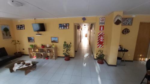 a living room with a couch and a tv on the wall at Hostal Km Zero - El Senor del Lascar in San Pedro de Atacama