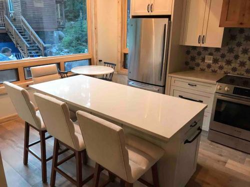 a kitchen with a white counter and chairs in it at Newly Renovated Creekside Cabin! in Almont