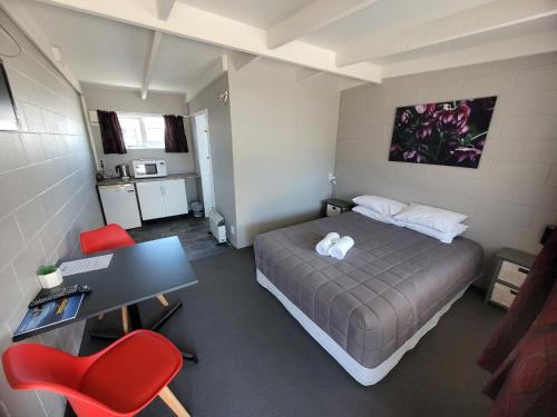 a bedroom with a bed and a desk and red chairs at Railway Hotel/Motel Hokitika in Hokitika