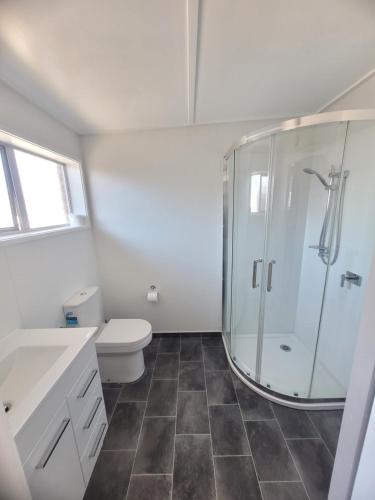 a bathroom with a toilet and a glass shower at Railway Hotel/Motel Hokitika in Hokitika
