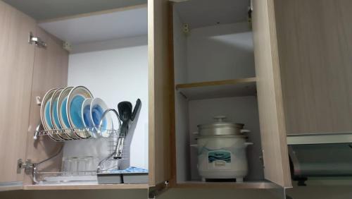 a cupboard with plates and utensils in it at Nahas Condo Hotel in Manila