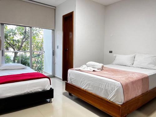 a bedroom with two beds and a large window at Hotel Sun River in Barranquilla