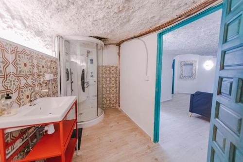 ein Badezimmer mit einem weißen Waschbecken und einer Dusche in der Unterkunft PRECIOSA CASA-CUEVA CON JACUZZI in Paterna