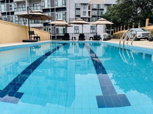 a large blue swimming pool with chairs and umbrellas at Embassy Access Golf Apartment in Kigali