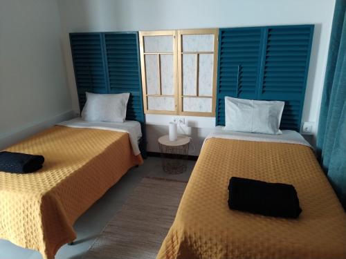 Duas camas num quarto com janelas com persianas azuis em Bus Stop House em Funchal