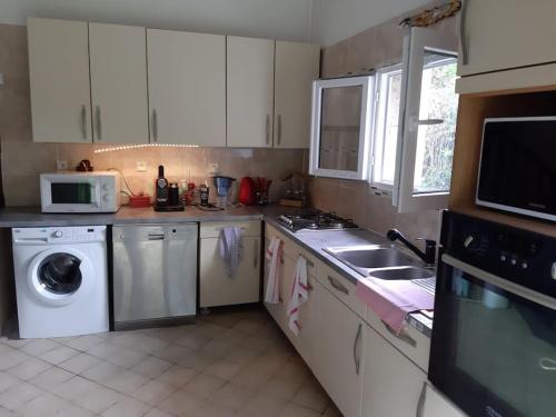 eine Küche mit einer Waschmaschine und einer Mikrowelle in der Unterkunft belle maison de campagne avec cheminée 