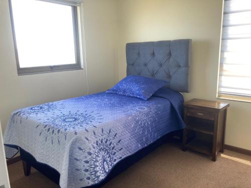 a bedroom with a blue bed and a night stand at Altavistamar in Viña del Mar