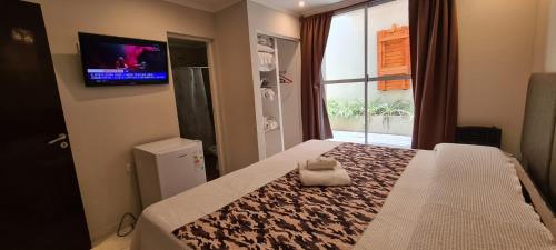 1 dormitorio con 1 cama y TV en la pared en Hotel Firenze en Necochea