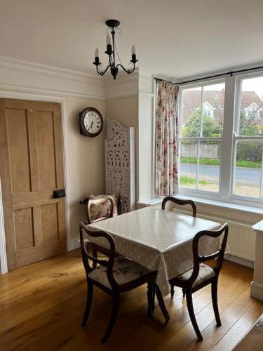 a dining room with a table and chairs and a clock at Beautiful, rustic bungalow in Reydon