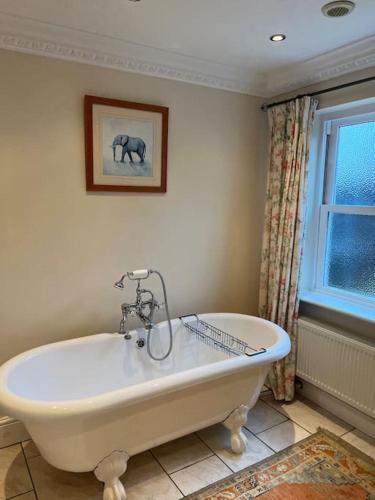 a white bath tub in a bathroom with a window at Beautiful, rustic bungalow in Reydon