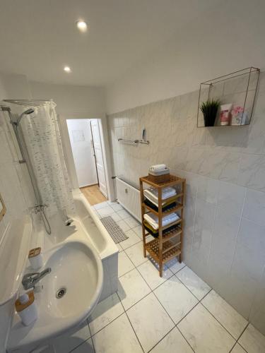 ein weißes Bad mit einem Waschbecken und einer Dusche in der Unterkunft Appartement La Vie en Rose in Essen