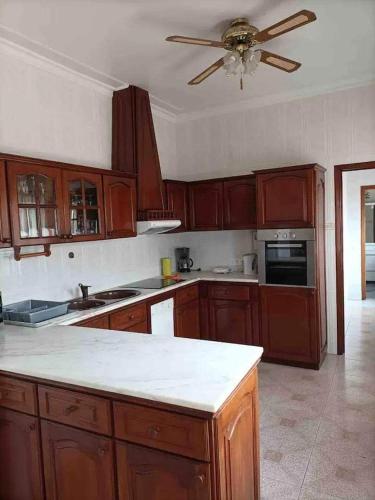 a kitchen with wooden cabinets and a ceiling fan at Azores House in Ponta Delgada
