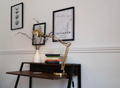 a desk with a lamp on a table with books at Hale Lodge in London