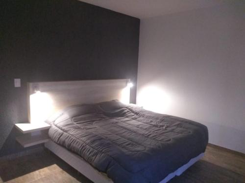 a bed in a bedroom with two lights on it at Anubis in Merlo