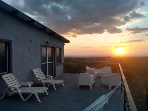 a group of chairs on a balcony with the sunset at Anubis in Merlo