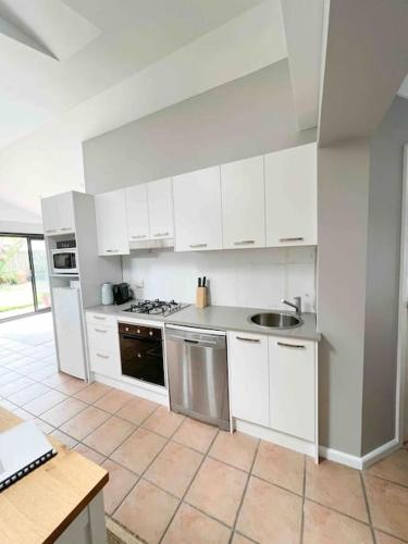 a kitchen with white cabinets and stainless steel appliances at Frangipani in Sydney